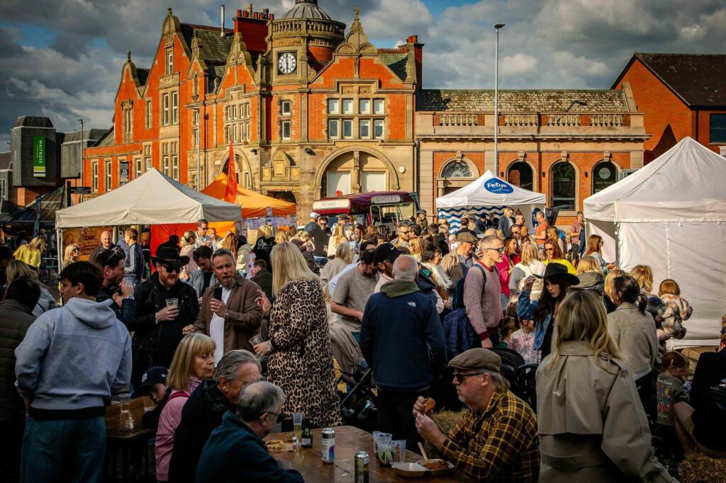 Crowds enjoying a vibrant outdoor street food market organised by The Market Co. in Wilmslow, Cheshire, featuring independent food vendors.